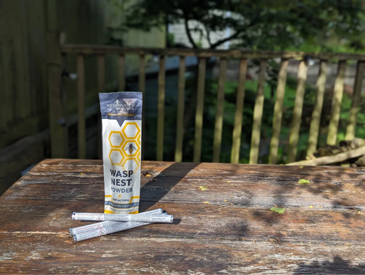 Wasp nest powder packaging on a wooden table with a blurred outdoor background