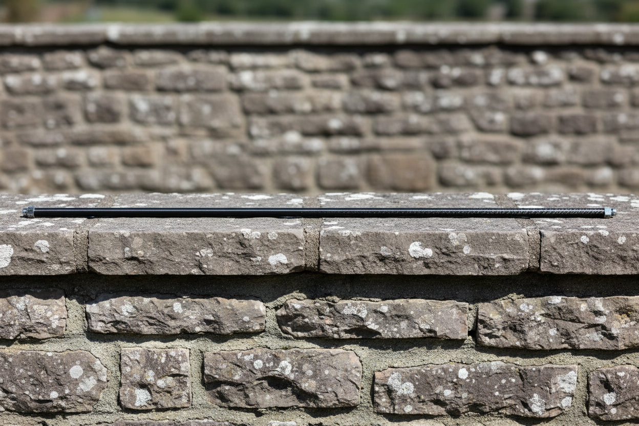 Long thin carbon fibre tube resting on a stone wall