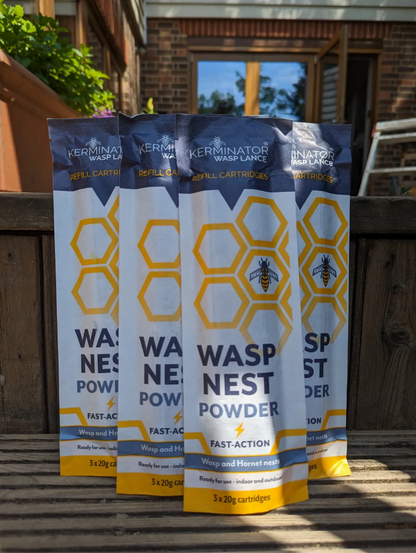 Four packages of Kerminator Wasp Nest Powder on a wooden surface with a garden background.