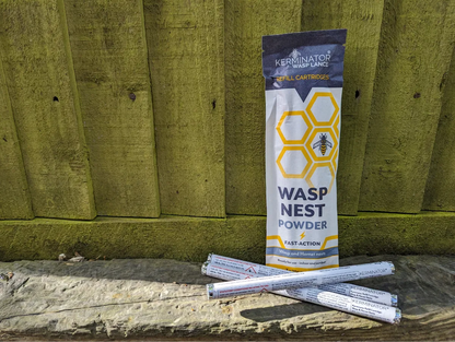 Kerminator wasp nest powder packaging on a wooden surface with a wooden fence background